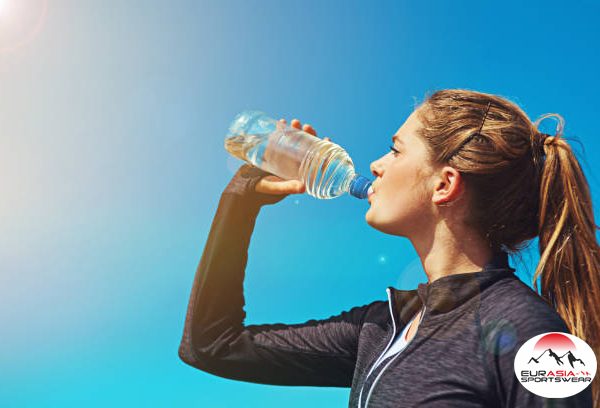 Shot of a sporty young woman drinking water outdoors